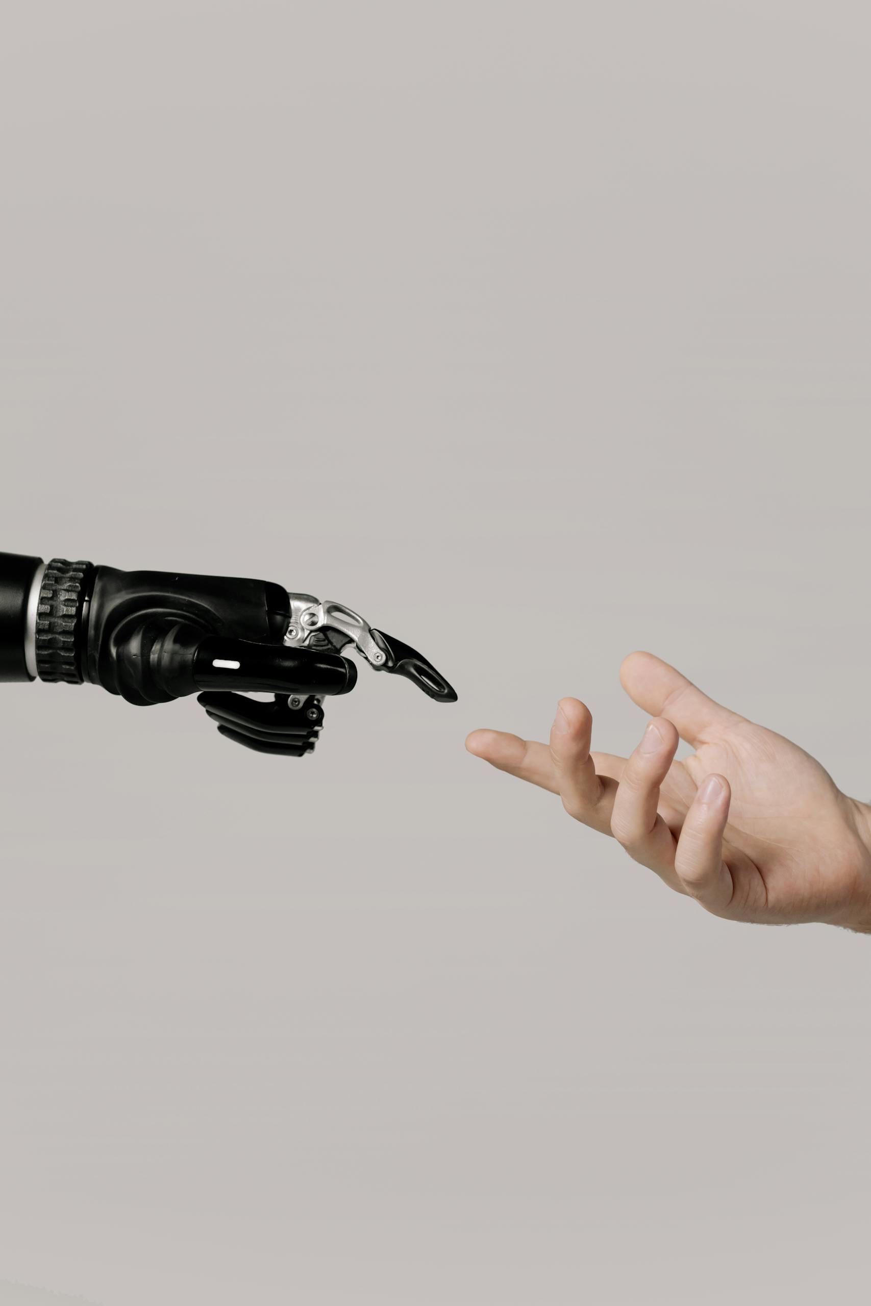 Personal AI. A human hand reaching to touch a bionic prosthetic hand on a white background.